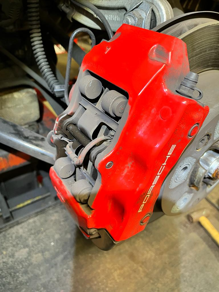 Porsche Cayenne red brake caliper before pad replacement