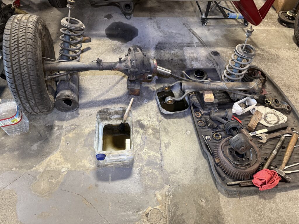 Mercedes SL190 rear suspension and differential fully disassembled in workshop showing axle, springs and drivetrain components