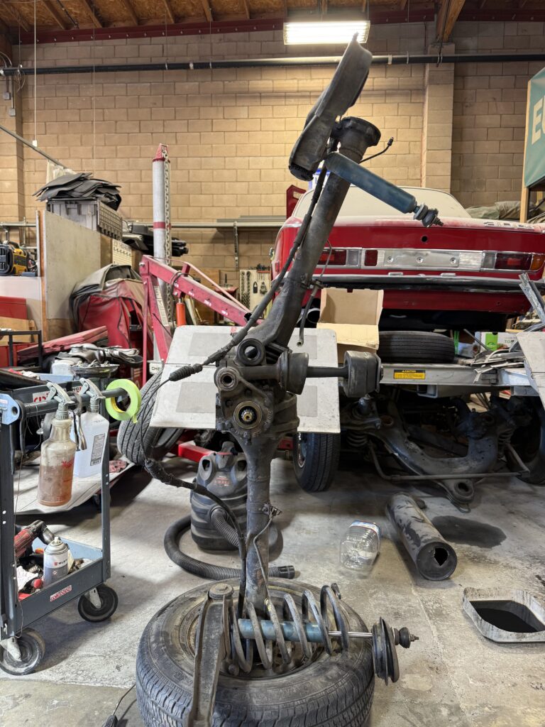 Mercedes SL190 rear suspension disassembly in workshop with axle, springs and shock absorber removed