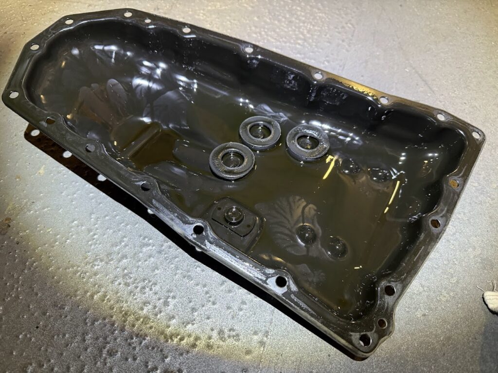 dirty engine oil pan with sludge buildup showing need for regular oil change and maintenance