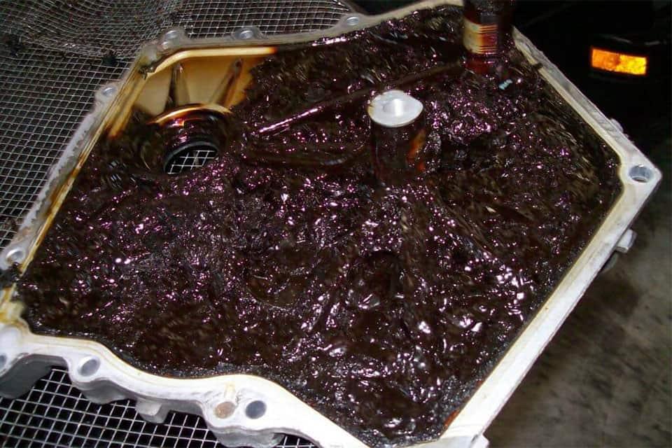 engine sludge buildup inside oil pan caused by neglected oil changes and poor maintenance
